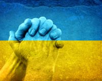 Ukrainian flag colored wall with hand clasped in prayer